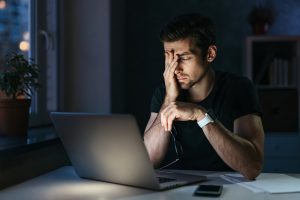 A man rubs his eye as he sits in front of a laptop in the middle of the night. A CBTI therapist in the United Kingdom can help you overcoming insomnia. Learn more about CBTI in the United Kingdom, including London, Surrey, Edinburgh and beyond in the United States as well.