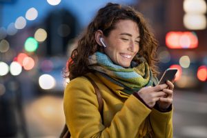 Image of a woman smiling on her phone. This is an image of someone who could be going to online therapy for expats. Learn more about expat counseling with an online therapist in the United Kingdom.